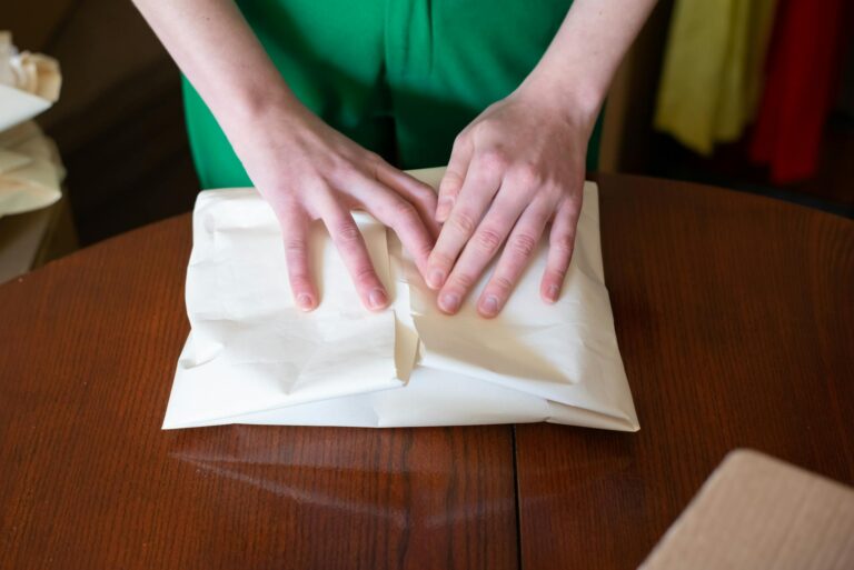Hands wrapping a parcel on a wooden table, Portugal setting.